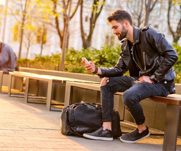 a,handsome,young,hipster,man,sitting,on,a,bench,in